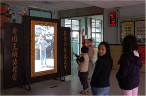 curious “participants” stand in front of the work, keen to see themselves or classmates behaving silly.